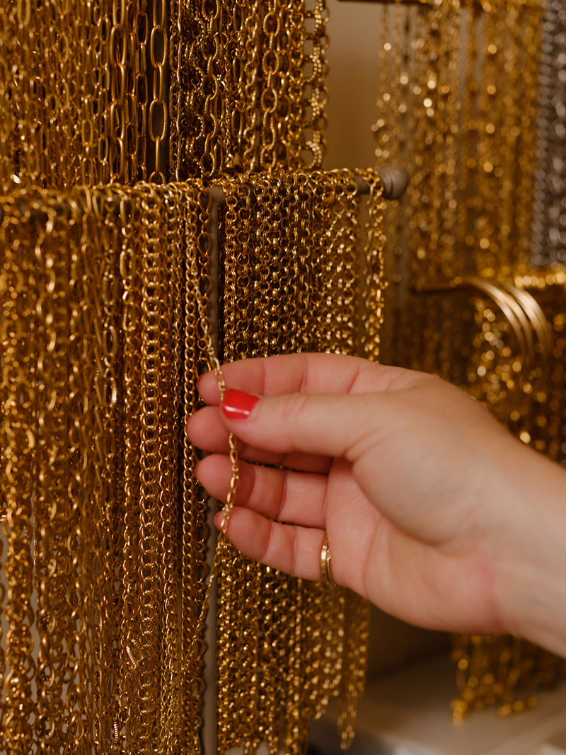 Hand holding a gold chain against a textured gold background